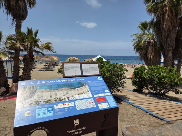 Beach rules and environmental information posted at Playa del Duque.