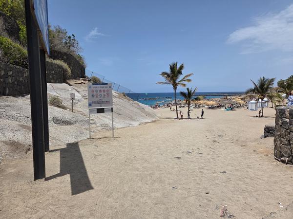 View of Playa del Duque with calm waters and visitors enjoying the beach.