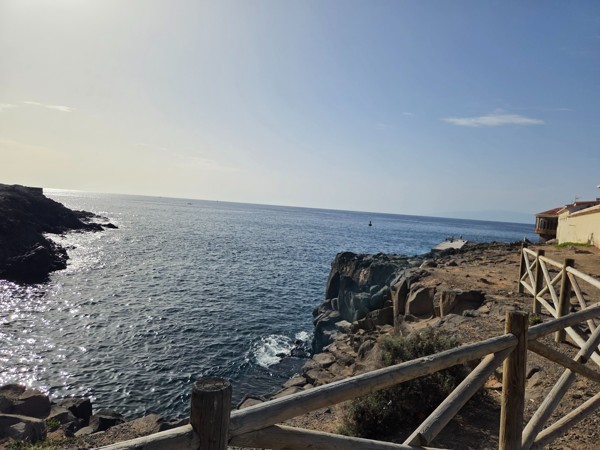 Wooden fence along the coastal path above Playa El Callao with open views of the Atlantic Ocean and the rocky point stretching into the sea.