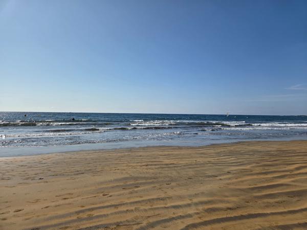 Golden sand and calm waves at Playa El Médano on a clear day.
