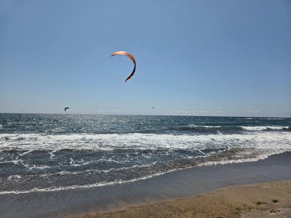 Orange kite flying above the waves, popular activity at Playa El Médano.