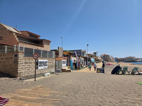 Windsurf and kite rental shops along the beachfront promenade of Playa El Médano.