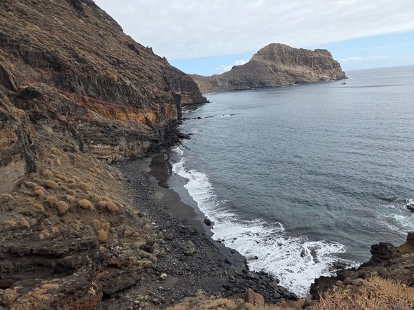 Panoramic perspective of Playa Itamar Diez with layered volcanic cliffs on the left and the massive rocky promontory closing the bay.
