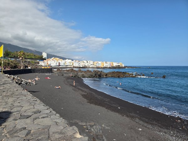 Sunny morning at Charcón sector of Playa Jardín with black lava sand and colourful houses of Punta Brava.