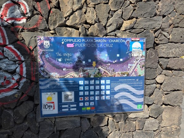 Information board for Charcón sector of Playa Jardín covered with graffiti.