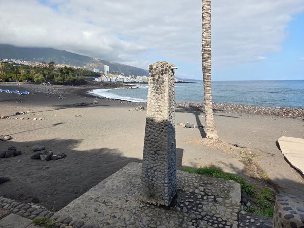 Volcanic-rock outdoor shower on the sand of Playa Jardín.