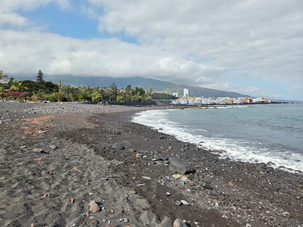 Wide panorama of Playa Jardín with Puerto de la Cruz and the mountains in the background.
