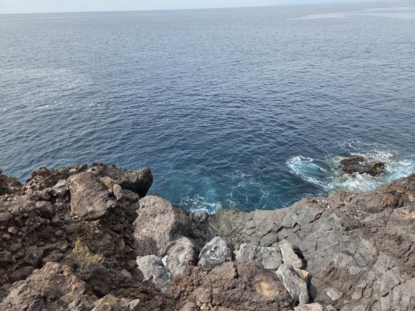 Sheltered nook of Playa de Ricasa enclosed by dark volcanic cliffs with the Atlantic beyond.