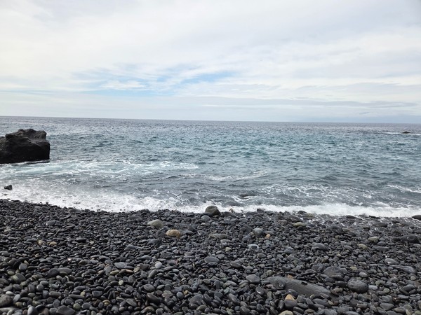 Atlantic water swirling around black volcanic rocks at the Ricasa shoreline.