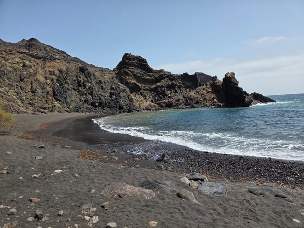 Curved bay of Playa de Roque Bermejo framed by dark volcanic cliffs and clear Atlantic water inside Anaga Rural Park.