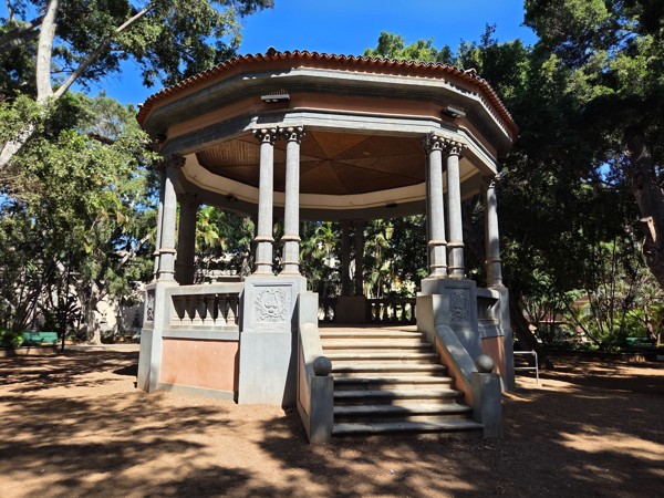 Central bandstand (kiosco de música) at Plaza del Príncipe de Asturias, surrounded by large ficus trees.