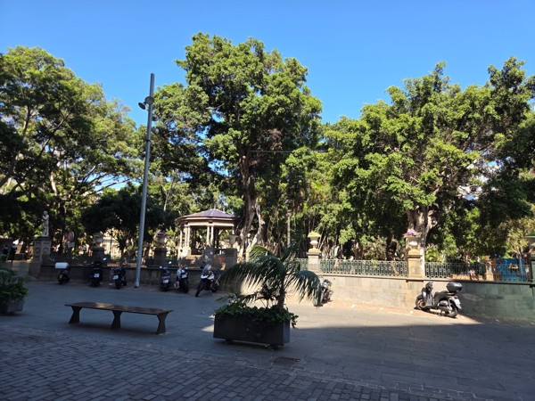 Wide view of Plaza del Príncipe de Asturias in Santa Cruz de Tenerife, with mature trees, bandstand and perimeter railing.