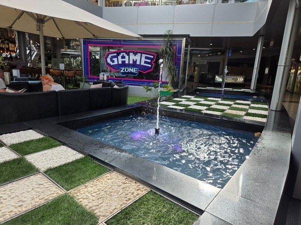 Fountains and lounge seating near the Game Zone backdrop in the atrium of Plaza del Duque.