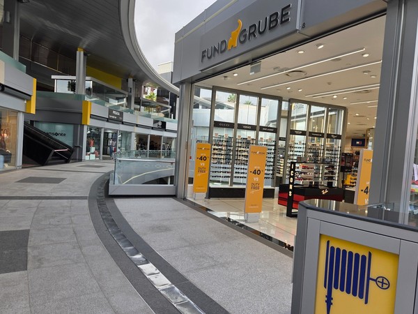 Fund Grube entrance with rows of sunglasses and beauty counters at Plaza del Duque.
