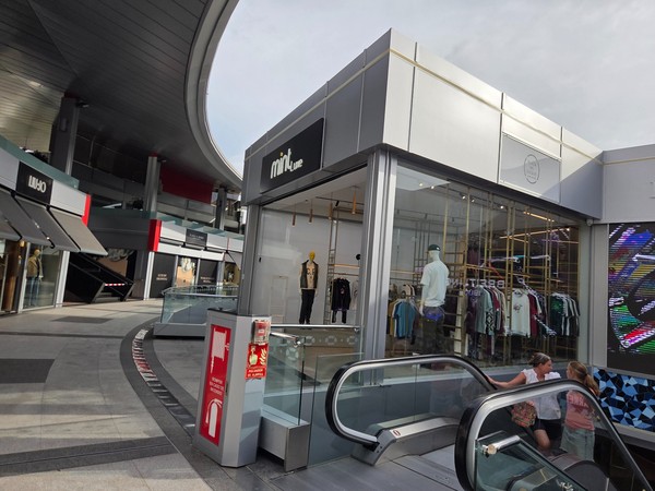 Corner unit of Mint with menswear rails and escalator access.