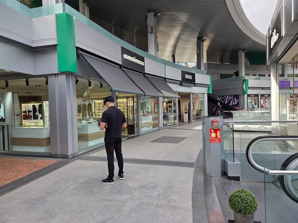 MultiÓpticas and BOSS storefronts on a curved terrace with glass balustrades.