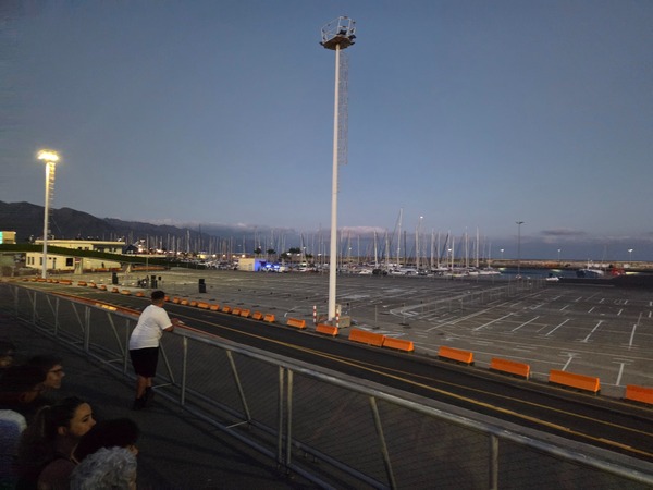 Dusk over the Santa Cruz de Tenerife marina with moored sailboats and people waiting along the harbor railing during Plenilunio.