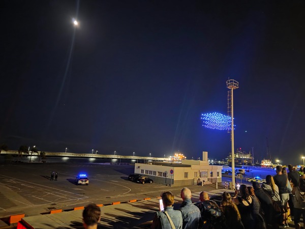 The first cluster of blue drones appears over the port of Santa Cruz at the start of the Plenilunio light show.