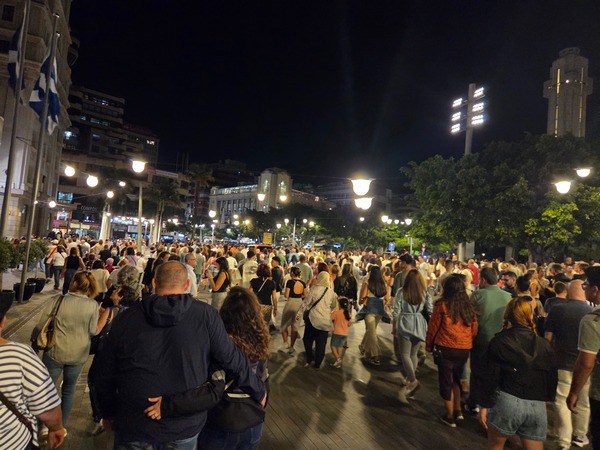 People walking under bright streetlights in the center of Santa Cruz de Tenerife after a Plenilunio concert.