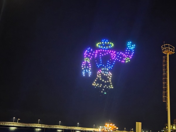 Humanoid figure with raised arm drawn by multicolored drones in the night sky over Santa Cruz de Tenerife.