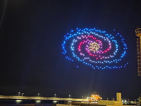 Large spiral galaxy traced by blue, pink and white drones above the breakwater in Santa Cruz de Tenerife.