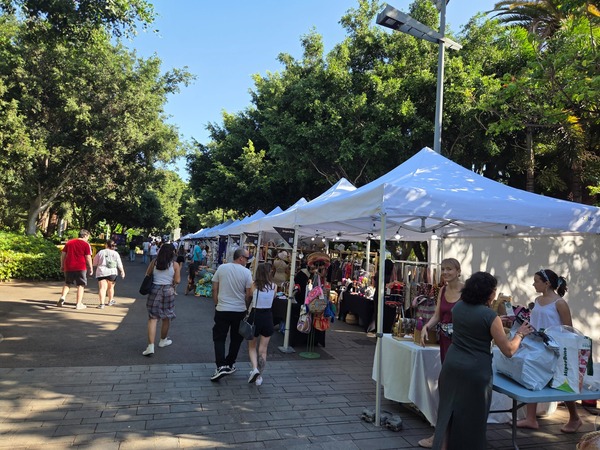 Panoramic view of the artisan marketplace with white tents lining the boulevard. Taken at Plenilunio 2025 in García Sanabria Park, Santa Cruz de Tenerife.