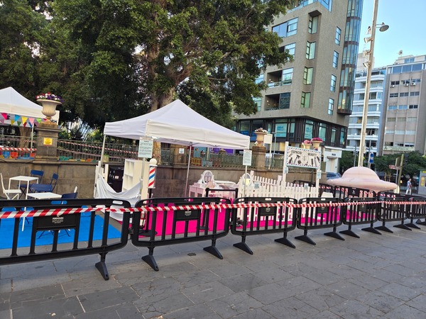 Continuous line of market stands under dense tree canopies with steady foot traffic. Taken at Plenilunio 2025 in García Sanabria Park, Santa Cruz de Tenerife.