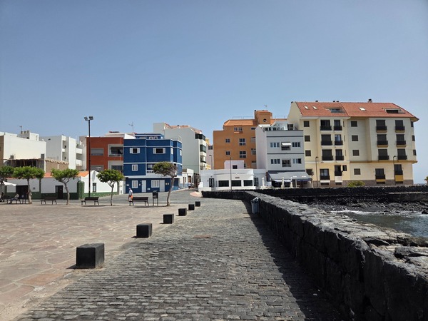 Colorful seafront apartment buildings facing the plaza and breakwater in El Puertito de Güímar.