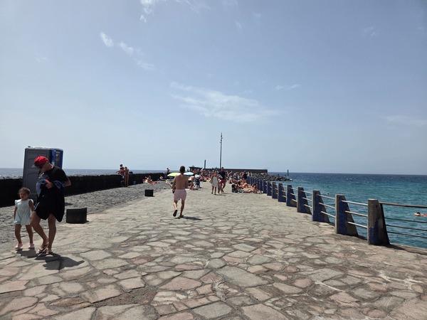 Crowds sunbathing on the long stone pier (muelle) at El Puertito de Güímar.