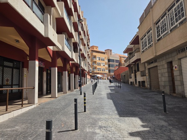 Pedestrian street lined with apartment buildings leading inland from the seafront in El Puertito de Güímar.