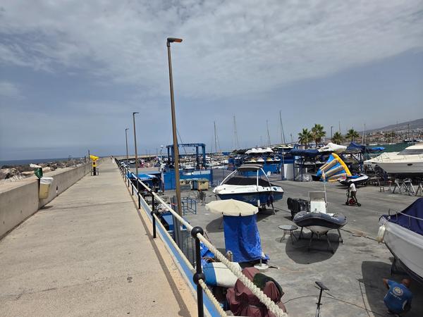 Roadside view of the harbor with vehicles, tourists, and the Puerto Colón lift