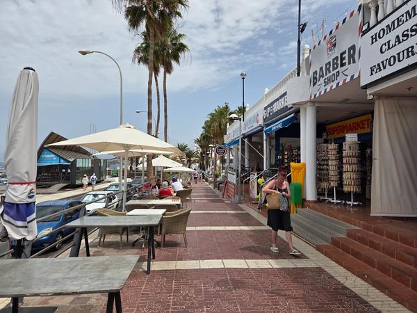 Shops and cafes near Puerto Colón marina with people walking and relaxing