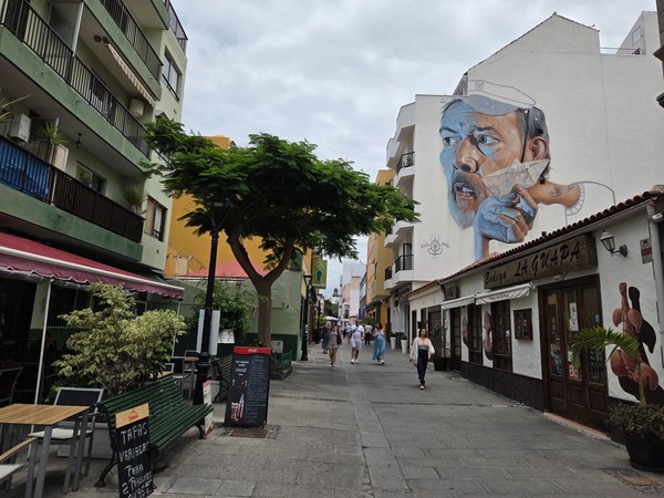 Street scene with a big mural of a sailor on a white wall in Puerto de la Cruz.