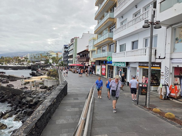 People strolling the seafront promenade with shops and cafés along the coast in Puerto de la Cruz.
