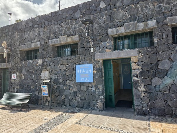Stone restroom block providing accessible toilets at Punta Brava Beach promenade.
