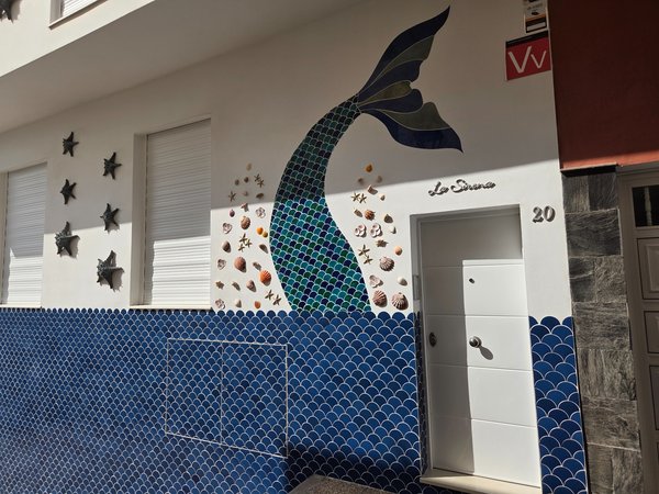 Facade decorated with a mermaid tail mosaic and seashells on a local holiday rental called La Sirena.