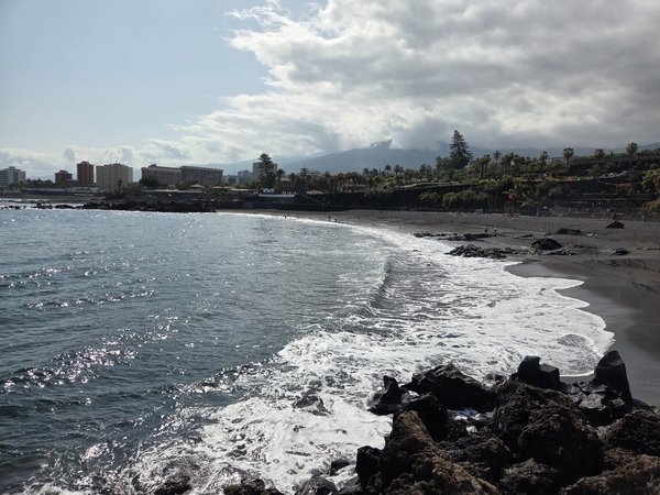 Panoramic view from the breakwater looking east along Punta Brava's black-sand shoreline.