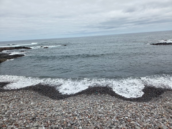 Pebble beach cove in Punta del Hidalgo with small waves breaking on the lava shore.