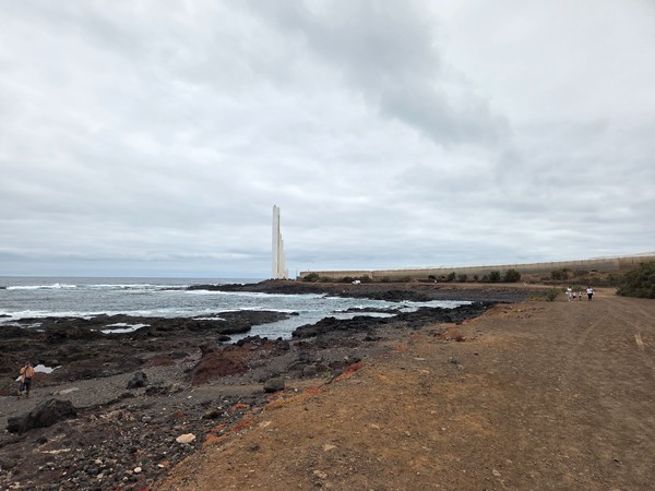 Rocky shoreline with the Punta del Hidalgo lighthouse visible in the distance.