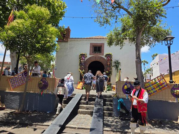 San Benito church entrance decorated for the romería with visitors arriving.