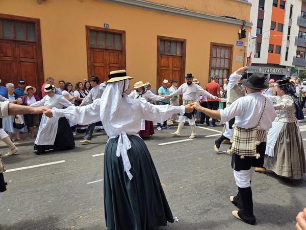People dancing in traditional folk costumes in a circle during the parade.