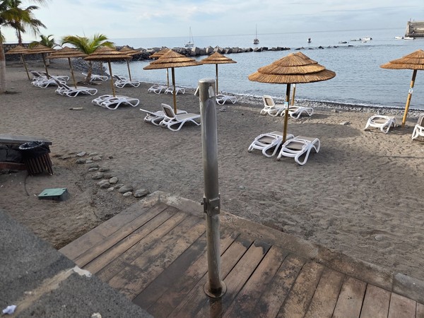 Sunbeds and straw parasols on the main beach of Playa San Juan within the protected bay.