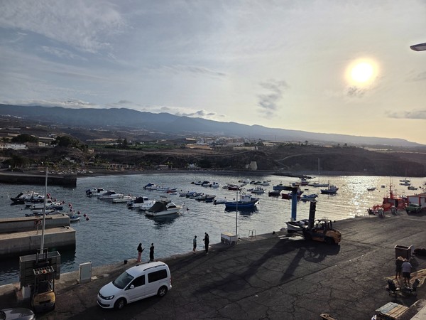 View across the fishing harbor of Playa San Juan with small boats moored inside the sheltered bay.