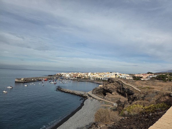 Panoramic view of Playa San Juan with the fishing harbor, promenade and seaside houses along the Guía de Isora coast.