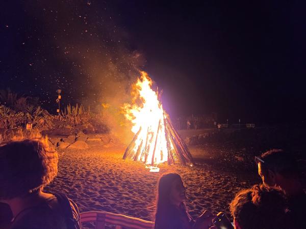 The San Juan bonfire fully ablaze on the beach, illuminating the night and surrounded by spectators.