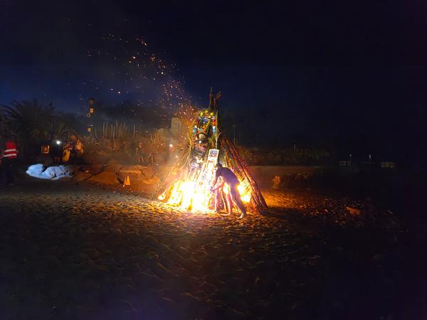A man ignites the large bonfire during the San Juan Festival as sparks fly upward into the sky.