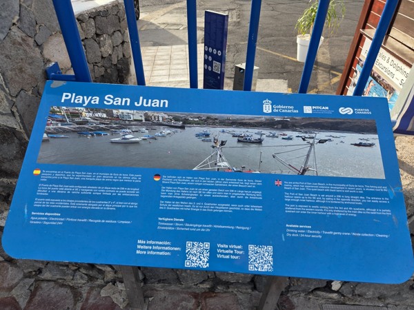 Harbor information panel titled Playa San Juan describing port services in Spanish, German and English.