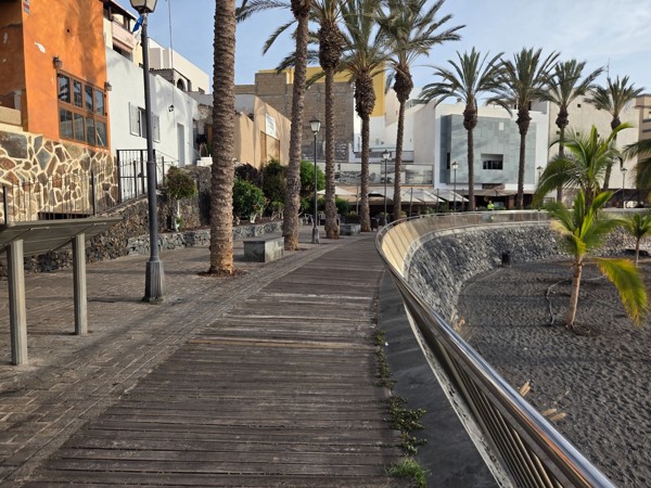 Cliffside path and stair access leading down to a quiet pebble cove south of Playa San Juan.