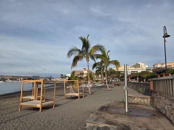 Stainless steel beach shower installed on a wooden platform by the sand at Playa San Juan.
