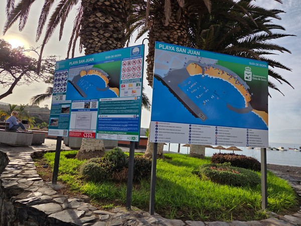 Information boards at Playa San Juan showing a beach map, safety guidelines, and services by the promenade.